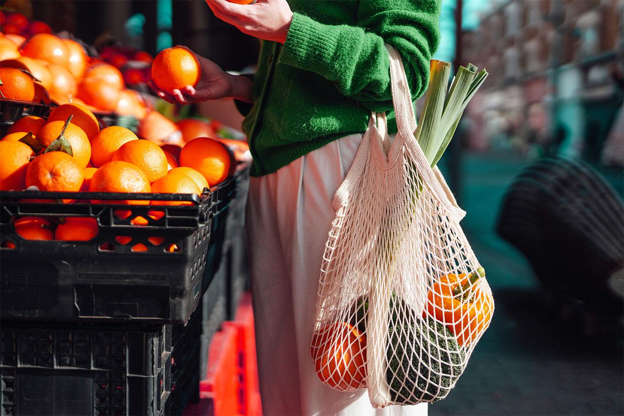 Person shopping with a bag of fruits and vegetables