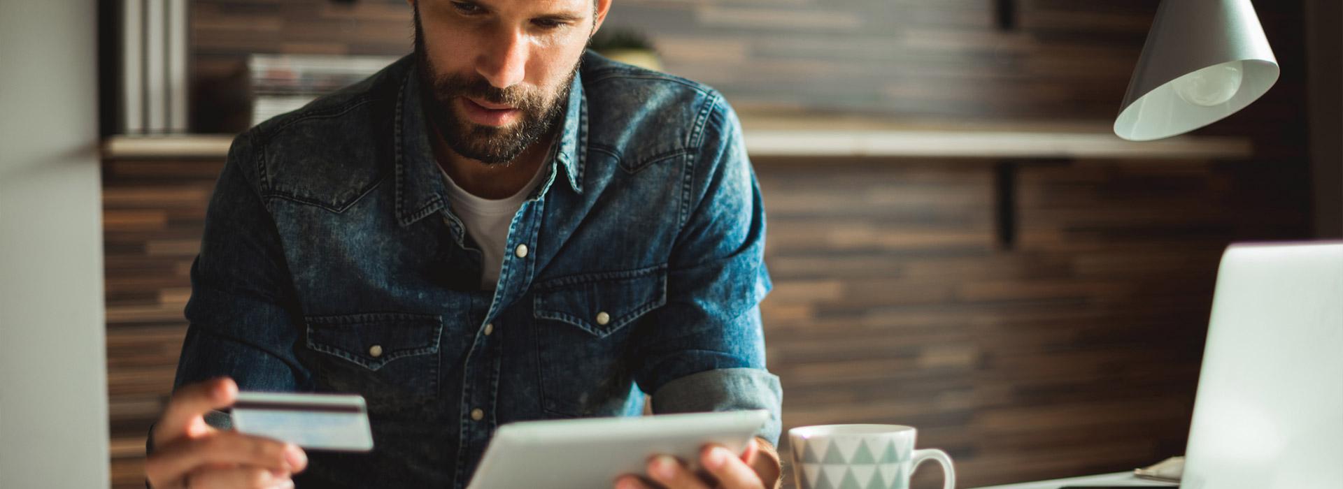 man looking a credit card and tablet