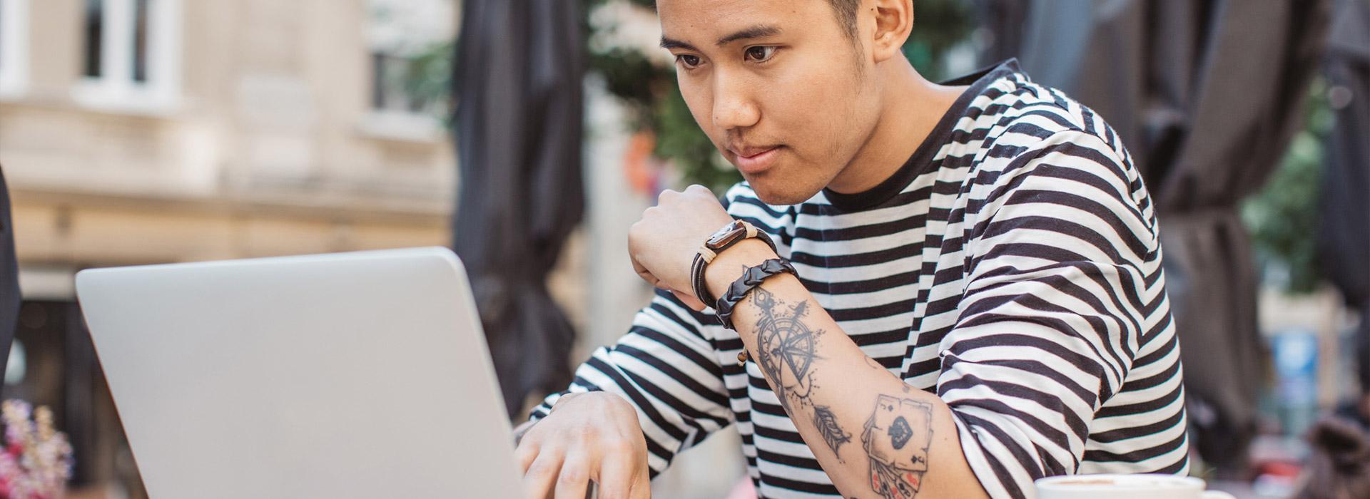 guy with tattoos looking at his laptop
